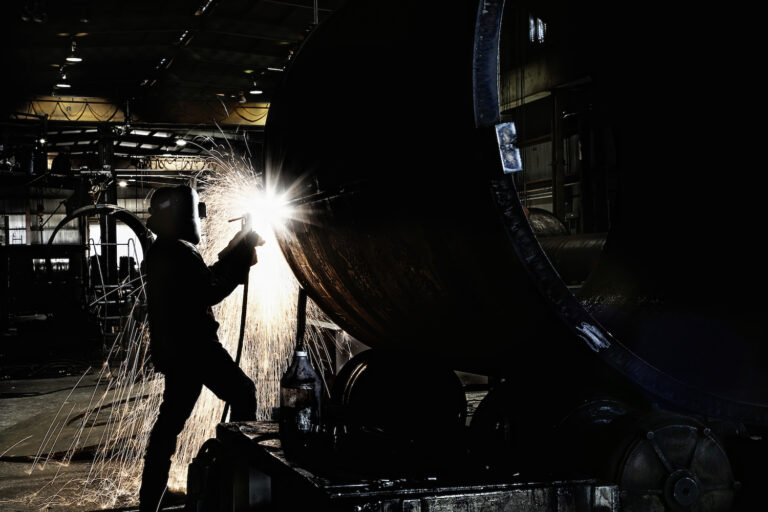 Man welding on machinery in an industrial setting