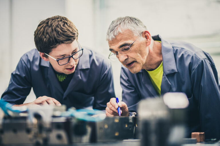 Senior engineer explaining machine functioning to his student