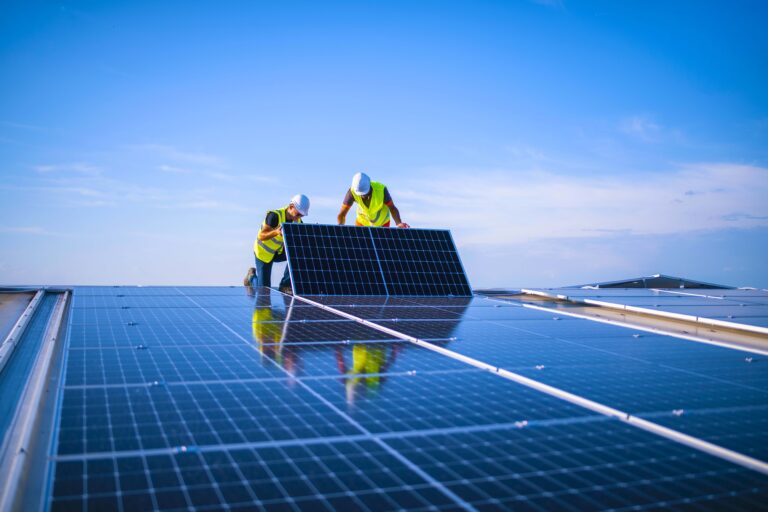 Two engineers installing solar panels on roof