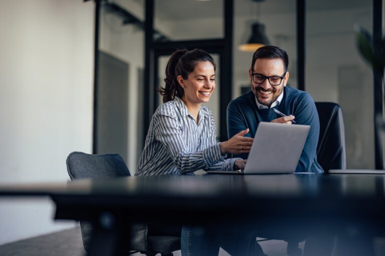 Smiling business people, looking at something over the laptop
